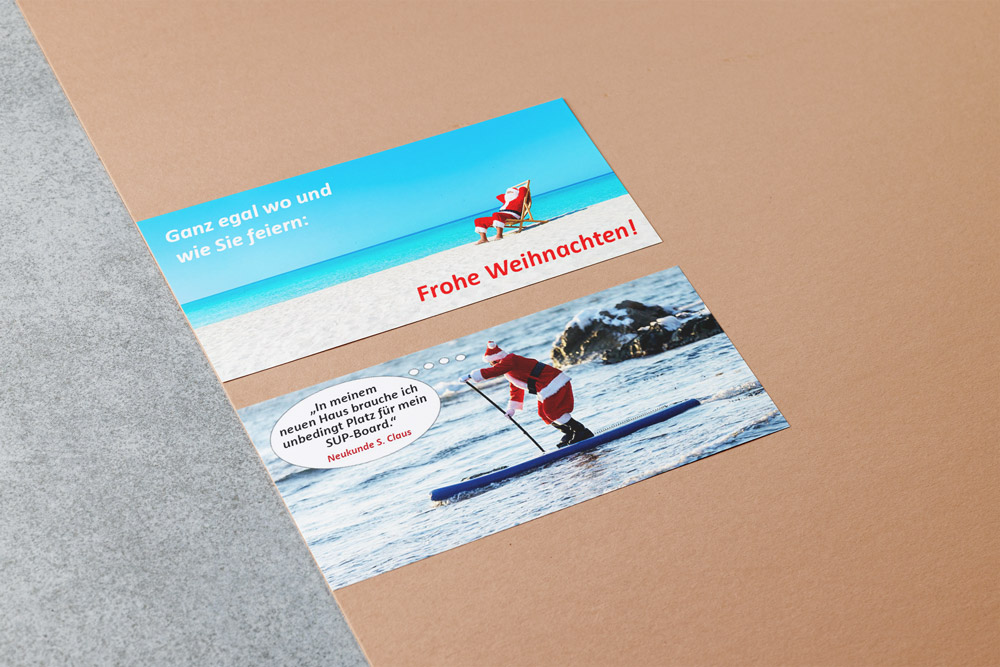 Weihnachtskarten für das Architekturbüro Eisenbraun und Eisenbraun Immobilien mit dem Thema "Strand". Eine Karte zeigt einen Weihnachtsmann am türkisfarbenen Südseestrand, das andere Motiv zeigt einen Weihnachtsmann auf einem SUP.