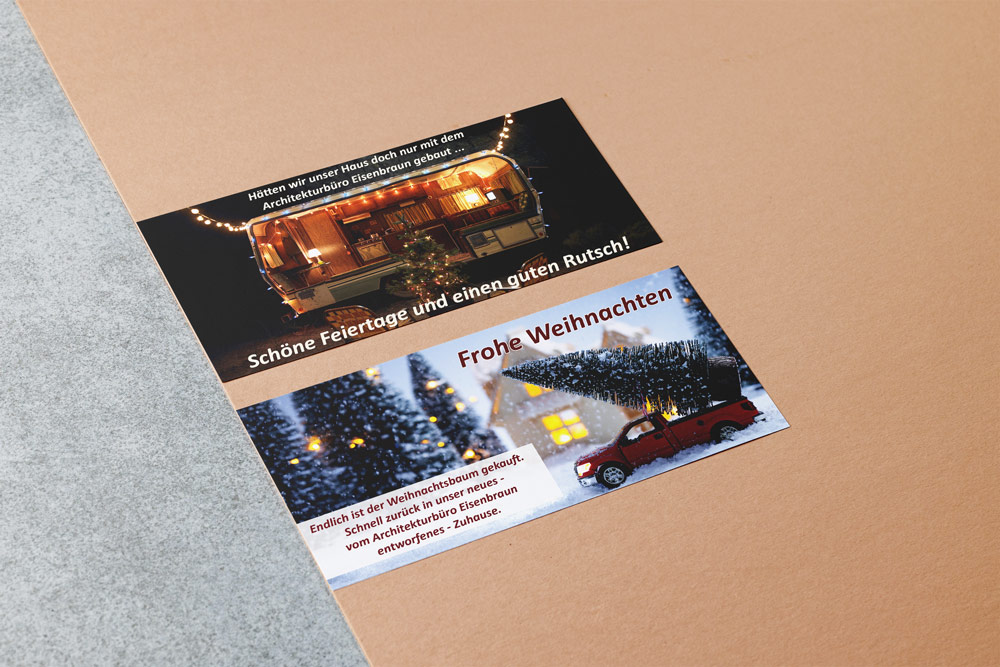 Weihnachtskarten für das Architekturbüro Eisenbraun und Eisenbraun Immobilien mit dem Thema "Unterwegs". Eine Karte zeigt einen Weihnahtsmann vor einem Wohnwagen, die andere Karte zeigt ein Spielzeugauto mit aufgeladenem Weihnachtsbaum.